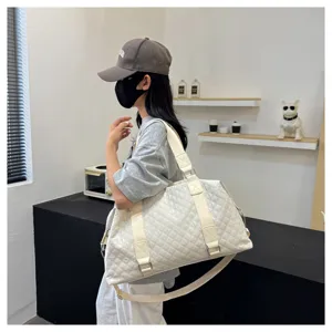 White quilted duffel bag detail showcasing large capacity and stylish shoulder strap design.