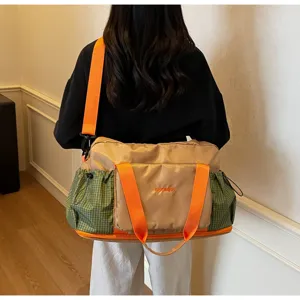 Detail shot of travel duffel fitness bag with orange straps and green side pockets.