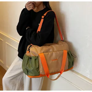 Spacious travel duffel bag with wet dry separation, stylish green plaid and orange straps.