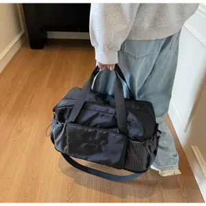 Detailed view of women's travel duffel bag with gym compartments and plaid side pockets.