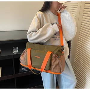 Detailed view of the olive green travel duffel bag with bright orange straps and side pockets.
