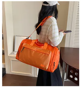 Detailed view of large capacity waterproof travel duffel bag in bright orange for gym use.