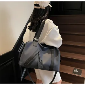 Vue de detail d'un grand sac de voyage gris avec fermeture eclair diagonale et sangle.