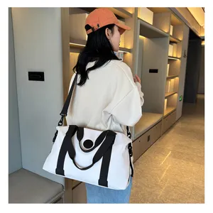 Detail view of large capacity white travel duffle bag with black straps for gym or weekend trips.