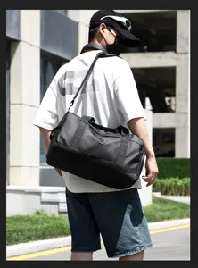 Vue détaillée du sac de voyage étanche noir porté par le modèle en extérieur, spacieux