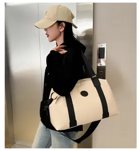 Detail view of the beige waterproof oxford cloth travel duffle bag with black straps.