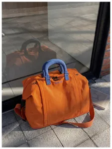 Large capacity travel duffel bag, stylish orange weekender with blue handles!