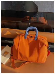 Large capacity travel duffel bag for women, short trip luggage with shoulder strap orange.