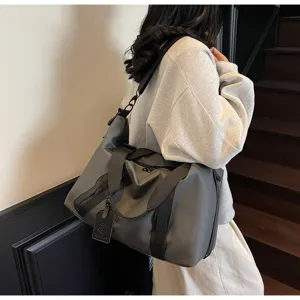 Vue détaillée du grand sac de voyage gris avec bandoulière et une étiquette élégante.