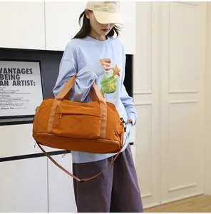 Detail view of the orange travel duffel bag showing front pocket and durable shoulder strap.