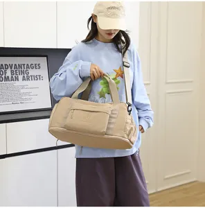 Detailed view of a khaki canvas travel duffel bag with front pocket and shoulder strap.