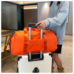 Orange travel duffel bag detail showing luggage sleeve on suitcase handle for easy transport.