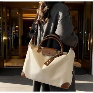 Grosse Reisetasche mit braunen Ledergriffen und wasserdichtem Stoff für Wochenendausflüge.