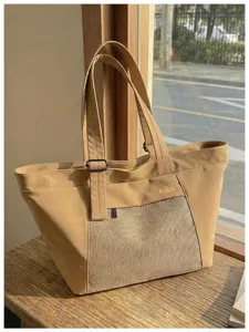 Detailed view of the beige canvas tote bag showing the woven front panel and shoulder strap.