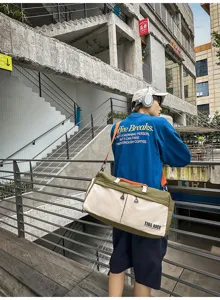Detalle de bolsa de deporte casual grande, mostrando correas naranjas ajustables y tela.