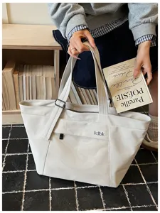 Detail shot of large canvas tote bag with front mesh pocket, casual commuting daily use style.