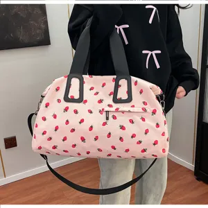 Nahaufnahme der rosa Kord-Reisetasche mit frischem Erdbeer-Print und schwarzen Griffen.