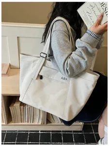 Detailed view of casual beige tote bag with mesh pocket and adjustable shoulder strap.