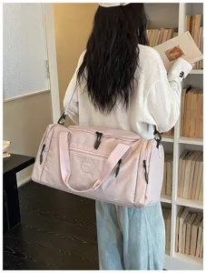 Pink travel duffel bag detail showcasing shoulder strap and waterproof fabric design.
