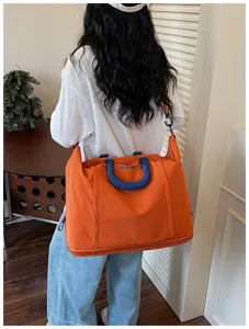 Detailed view of the large capacity travel duffel bag in vibrant orange with blue accents.