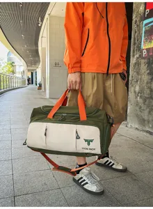 Detail view of nylon travel duffel bag with multi-pocket storage and orange straps in urban setting.