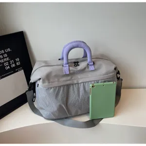 Detail view of large capacity travel duffel bag with purple handles and grey fabric design.
