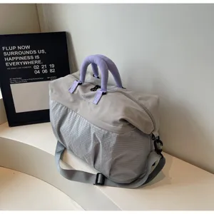 Detail view of large capacity expandable travel duffel bag with purple handles and gray fabric.