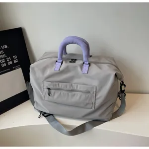 Detailed shot of a grey sports gym travel duffel bag with purple handle wrap and front pocket.