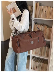 Detail view of brown travel duffel bag showing durable fabric, sturdy zippers, and shoulder strap.
