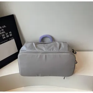 Detail view of grey expandable travel gym bag with mesh texture and purple top handle.
