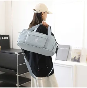 Detail view of light blue waterproof travel duffel bag with shoulder strap and front zip pocket.