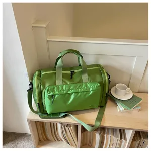 Green travel duffel bag detail, showing waterproof nylon fabric, front pocket and sturdy handles.