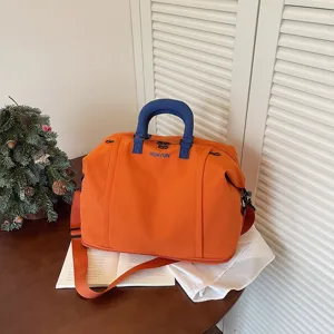 Large capacity travel duffel bag for women, orange weekender bag with blue handles and strap.