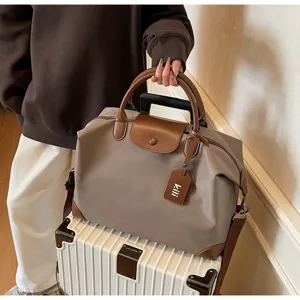 Detailansicht einer großen Reisetasche mit braunen Lederakzenten und stabilen Handgriffen.