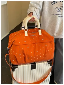 Orange polka dot travel duffel bag detail, expandable large capacity luggage storage bag.