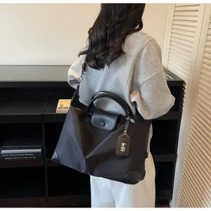 Detailaufnahme des schwarzen Nylon-Reisebeutels mit Ledergriffen und praktischem Überschlag.