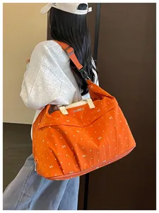 Detail view of the orange travel duffel bag with cute bow patterns and large capacity.