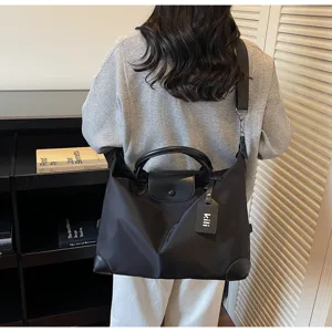 Große schwarze Nylon-Reisetasche mit Tragegriff und verstellbarem Schultergurt für den Alltag.