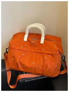 Expandable orange travel duffel bag with polka dot pattern, large capacity luggage bag.