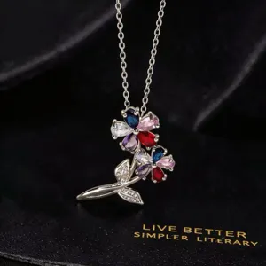 Primer plano de un collar con colgante floral de circonita multicolor en fondo texturizado.