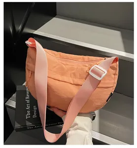 Λεπτομερής εικόνα της casual πορτοκαλί τσάντας χιαστί με φαρδύ λουρί σε σκούρα σκαλοπάτια