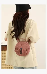 Vue détaillée du sac bandoulière rond élégant en rose, avec cordon de serrage et poignée.