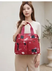 Vue détaillée du sac à langer rouge à motif d'étoiles avec poignées de transport.