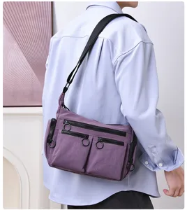 Detail shot of purple multi-pocket crossbody bag with ring zippers and comfortable shoulder strap.
