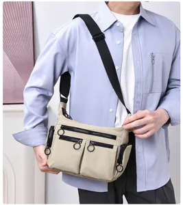 Close-up detail of the multi-pocket workwear canvas crossbody bag with ring-pull zippers.