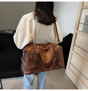 Detailed view of large capacity waterproof travel duffel bag in brown leather style for gym.