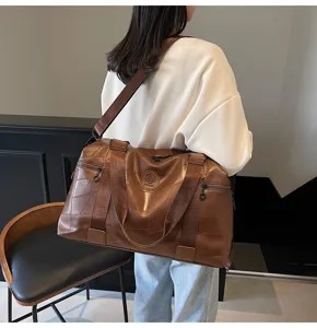 Brown large capacity travel duffel bag for gym and sports with shoulder strap and handles.