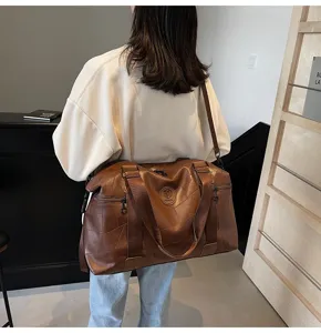 Details of the brown leather travel bag showcasing large capacity and sturdy shoulder straps.