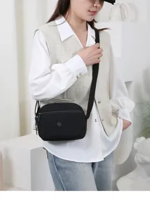 Gedetailleerd overzicht van een zwarte, meerlaagse casual nylon schoudertas door model.
