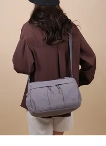 Vue détaillée du sac bandoulière en nylon gris porté par le modèle avec poches multiples.